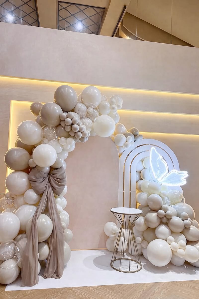 Arche de ballons ivoire et beige avec un papillon lumineux