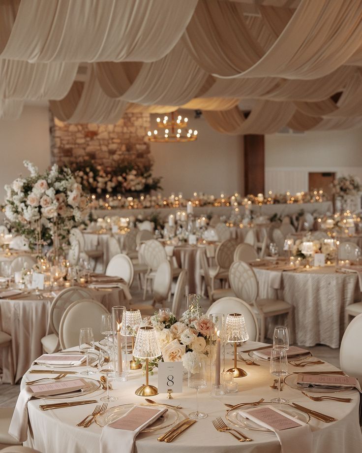 Salle de réception aux plafonds drapés, tables dorées et centres de table floraux